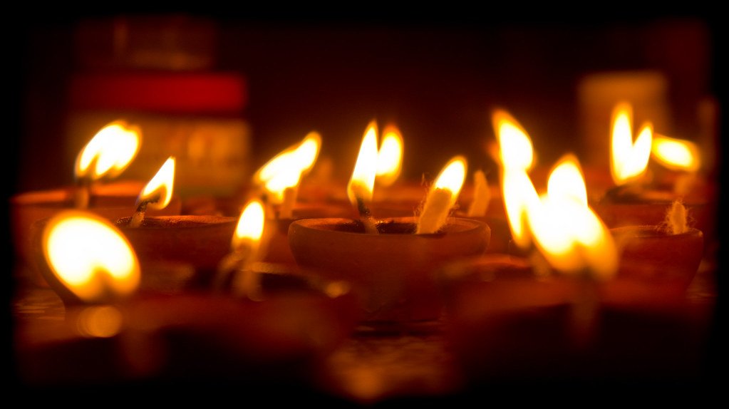 Rows of lit clay diyas glowing in the dark for Diwali