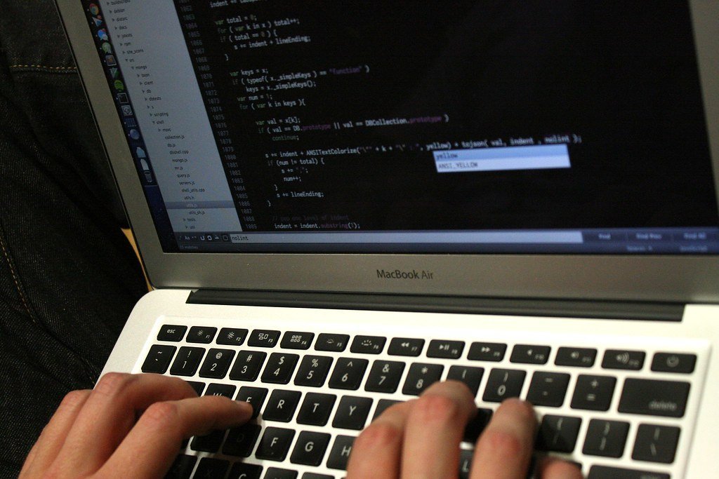 Close-up of hands typing code on a laptop keyboard