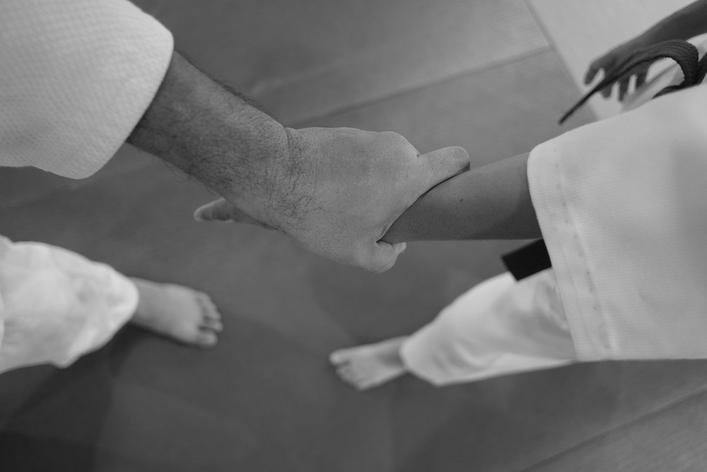 Two karate practitioners in white gi clasping hands during a training session