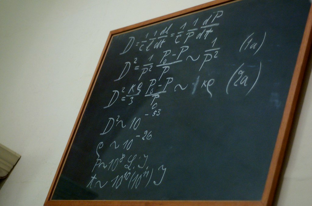 Mathematical equations handwritten in chalk on a blackboard